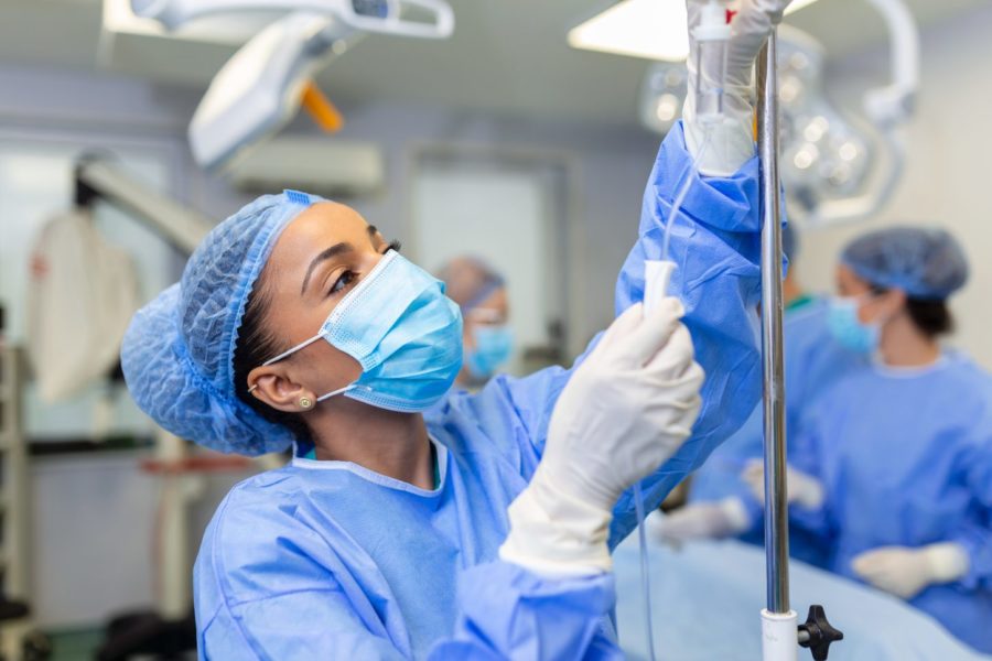 African American female Doctor in the operating room putting drugs through an IV