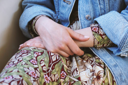 mid section of young woman wearing denim jacket over summer dress with floral pattern