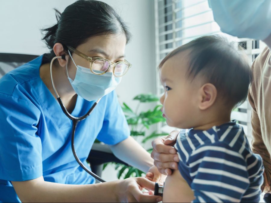 Asian Doctor Examining And Listening Lungs Of Little Baby Boy Wi