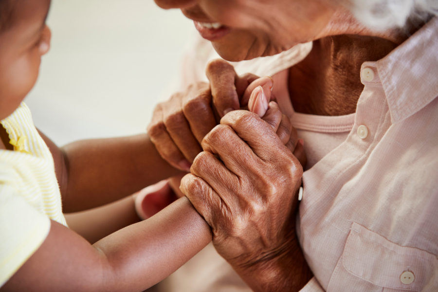 Close Up Of Grandmother Holding Hands With Baby Granddaughter Playing Game Together