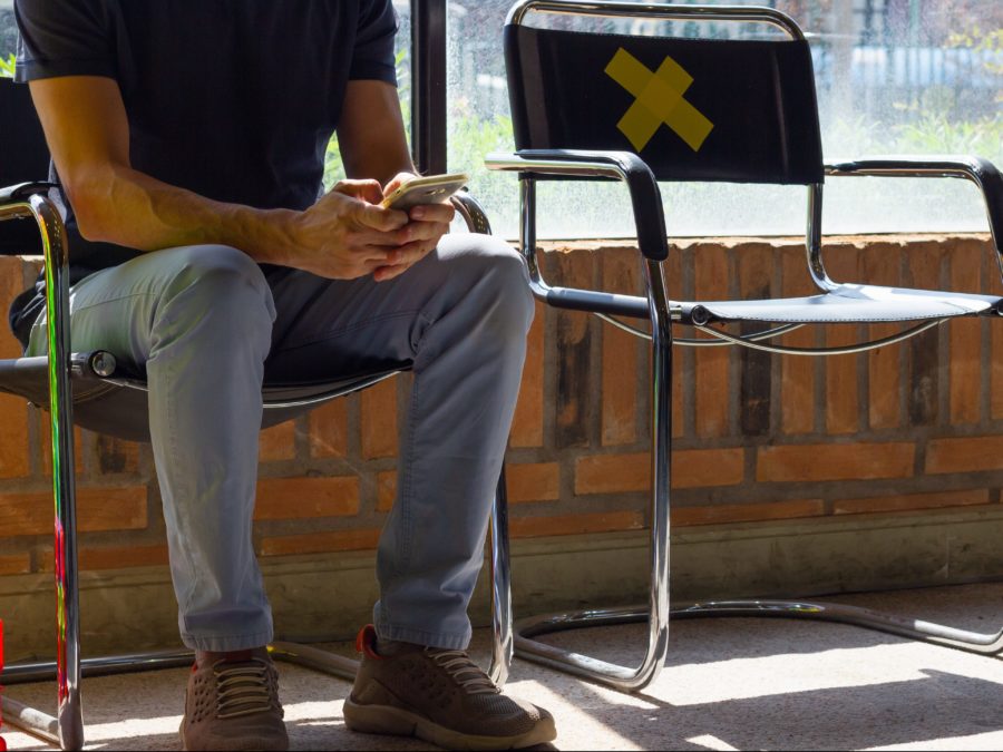 Anonymous Man Sitting Down Using Cell Phone At Doctor's Waiting